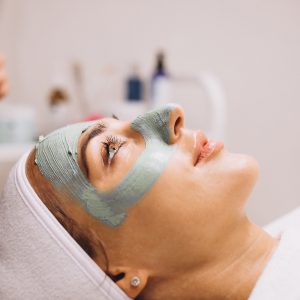Cosmetologist applying mask on a face of client in a beauty salon